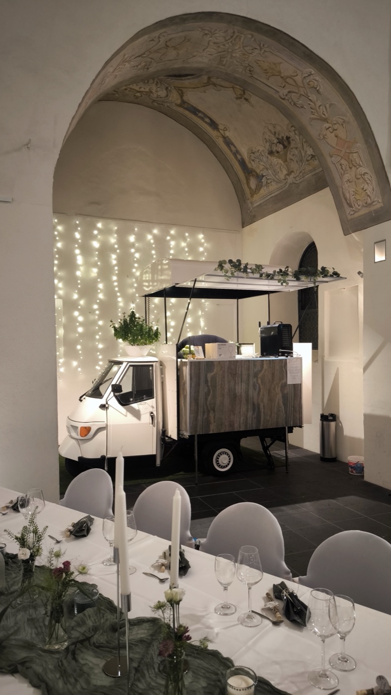 Festlich gedeckte Hochzeitstafel unter einem historischen Gewölbebogen, im Hintergrund die Ape-Bar