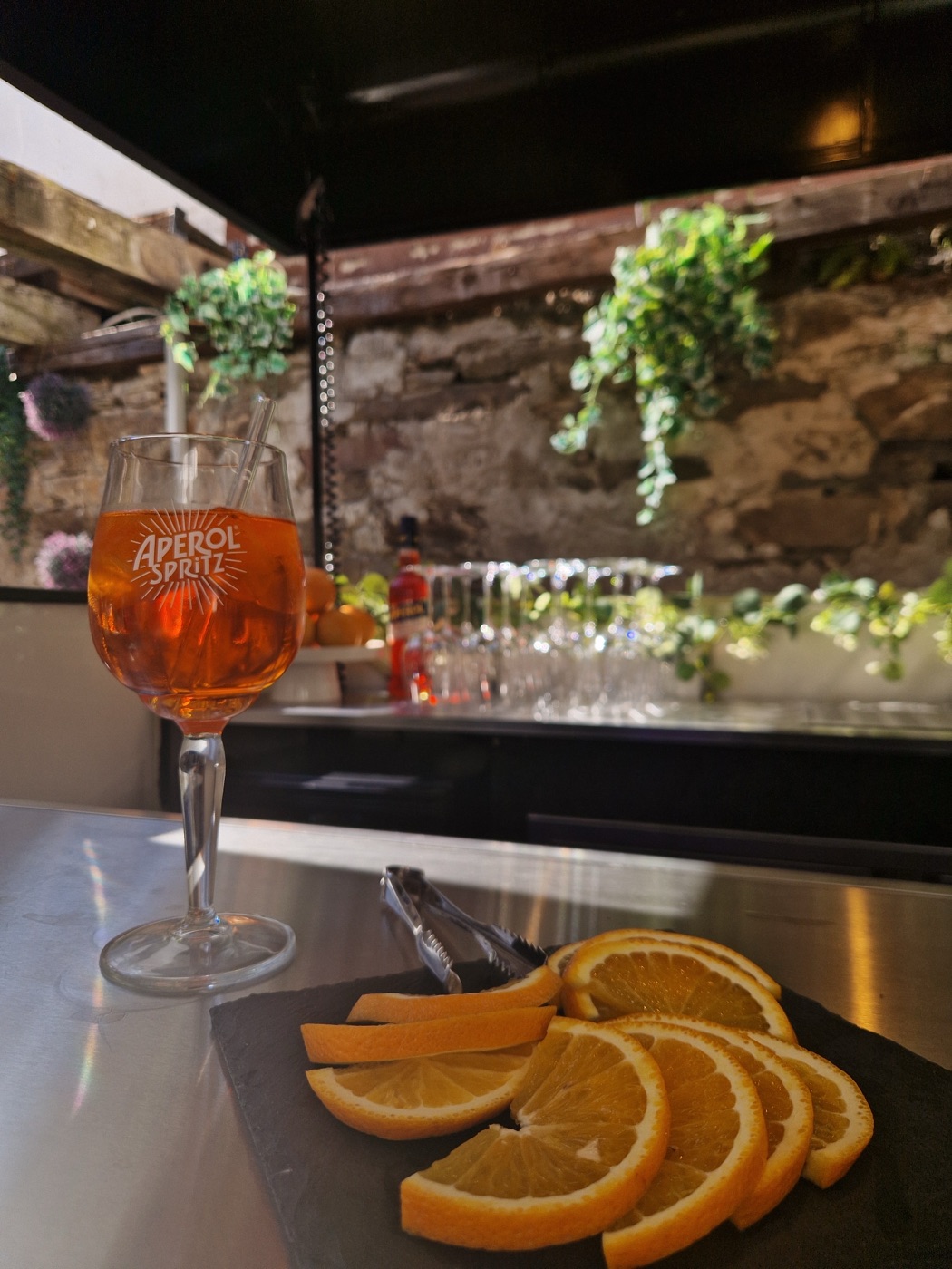 Aperol Spritz im Glas neben frisch geschnittenen Orangenscheiben auf der Bar